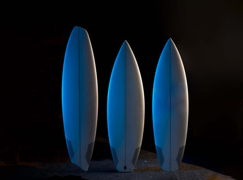 Three logo-less surfboards in blue light. 