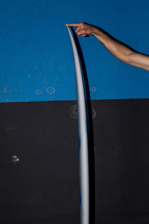 Side angle of a surfboard displaying the nose rocker. 