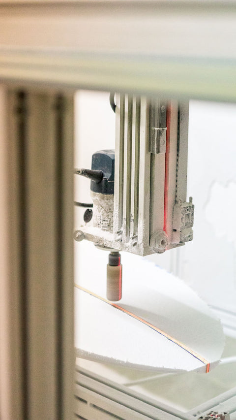 A CNC machine shaping a surfboard. 