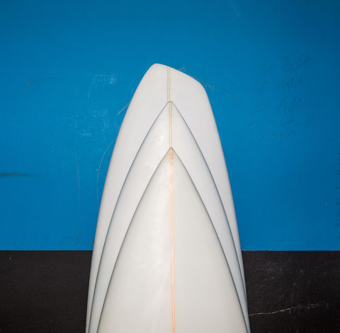 Three custom surfboards on a blue and black wall.