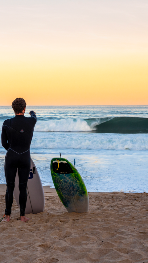 Surfer with custom surfboard points at wave